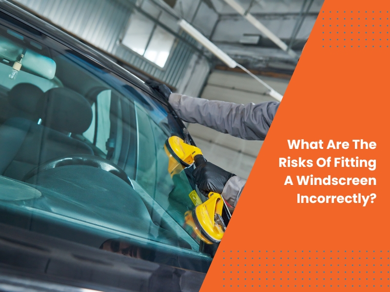 Technician fitting a windscreen using suction cups in a garage, ensuring correct placement and safety.