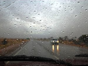 Car driving in the rain, experiencing windscreen noise from water hitting the glass and airflow disruption.