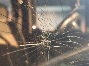 Close-up of a windscreen crack with radiating lines, showing damage to the laminated glass of a vehicle.